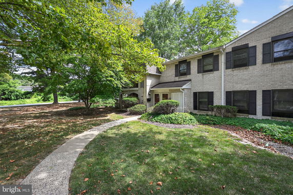 Front view of a two-story house with brick exterior and dark shutters.