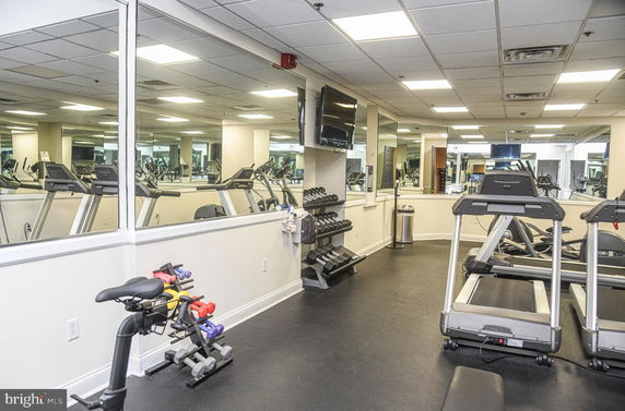 Interior view of a gym area with exercise equipment and mirrors.