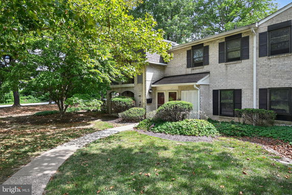 Front view of a two-story house with a brick exterior and dark shutters.