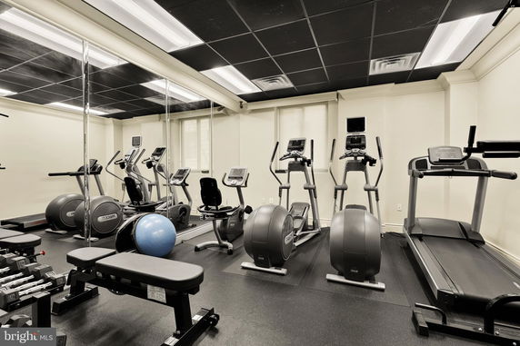 Indoor gym area with exercise equipment including treadmills, ellipticals, and weights.