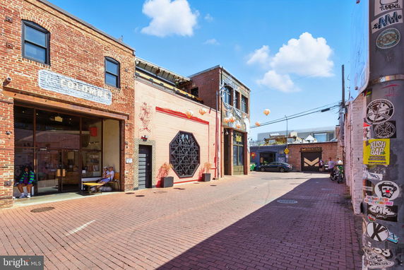 Front view of brick buildings in an alley with a cafe and shop signs.
