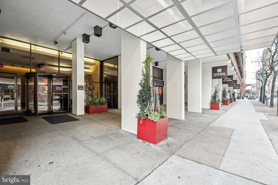 Front view of a commercial building entrance with glass doors and red planters.