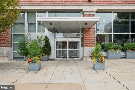 Front view of a modern building with a brick facade and large entrance doors.