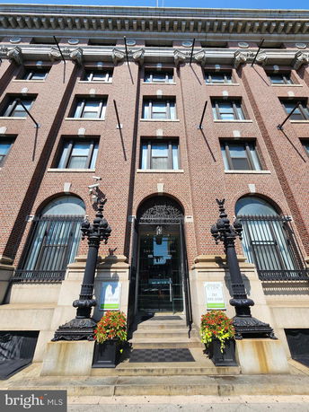 Front view of a multi-story brick building with decorative elements and entrance steps.