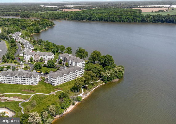 Aerial view of a residential complex surrounded by greenery and a large body of water.