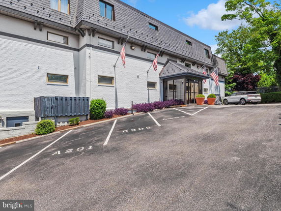Front view of a building with a sloped roof and parking area in front.