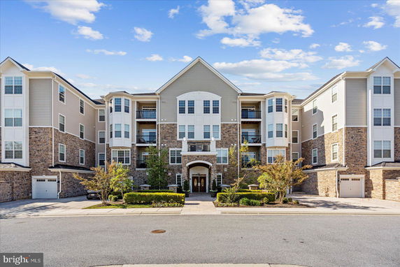 Front view of a multi-story residential building with balconies and stone detailing.