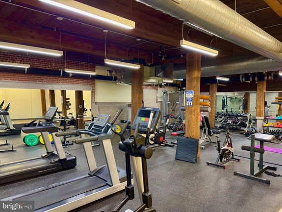 Indoor gym area with exercise equipment and weights.