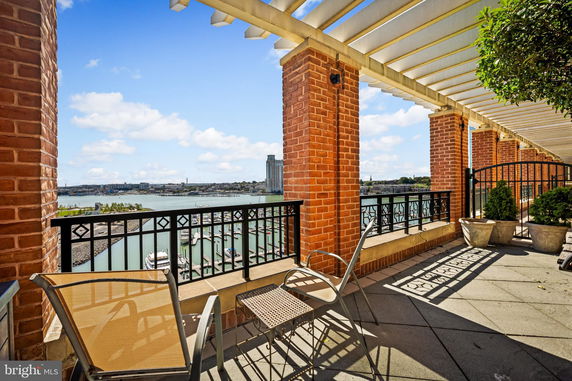Terrace with brick columns overlooking a water view and cityscape.