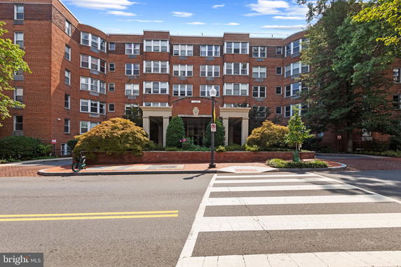 Front view of a multi-story brick building with a landscaped entrance.