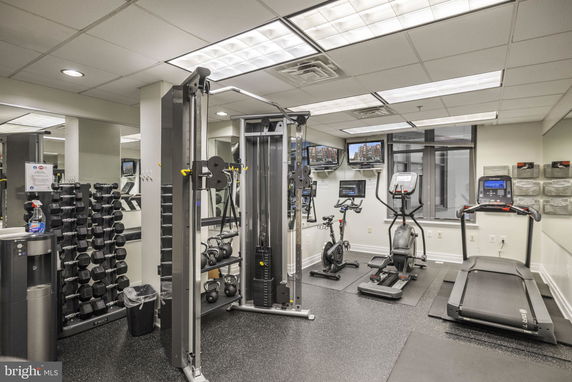 Indoor gym with exercise equipment including treadmills, stationary bikes, and weight station.