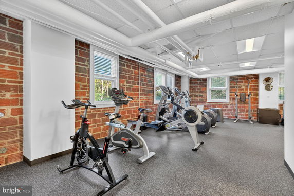 Indoor gym area with exercise equipment and exposed brick walls.