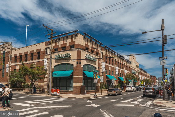 Front view of a multi-story commercial building with brick facade and teal awnings.