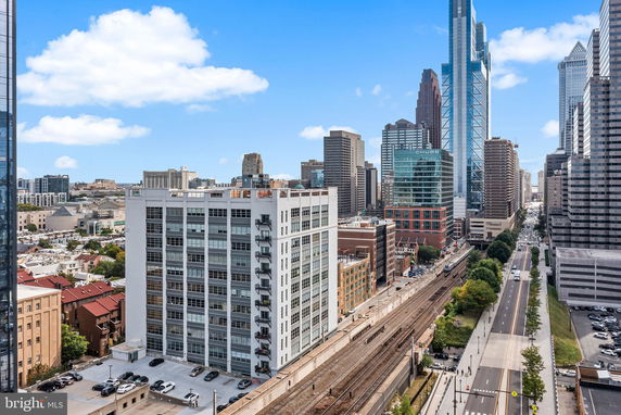 Panoramic view of a cityscape with tall buildings and a railway line.