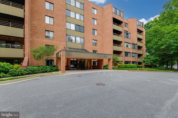 Front view of a multi-story brick apartment building with a covered entrance.