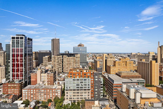 Panoramic view of a city skyline with multiple high-rise buildings under a clear blue sky.