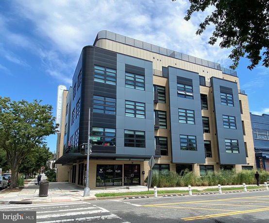 Front view of a modern multi-story commercial building with black and gray paneling.