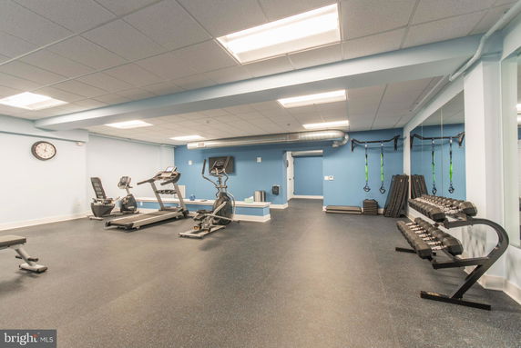 Interior view of a gym room with exercise equipment and weights.