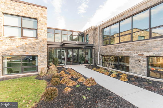 Front view of a modern building with stone exterior and large glass windows.