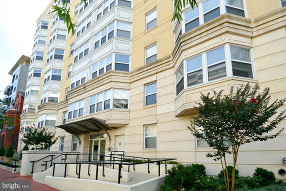 Front view of a multi-story residential building with large windows and a modern entrance.