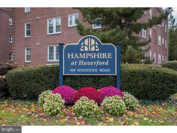 Front view of a brick apartment building with sign displaying 'Hampshire at Haverford'.