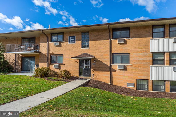 Front view of a two-story brick apartment building with balconies and air conditioning units.