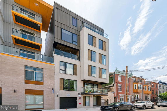 Front view of a modern multi-story building with large windows and balconies.