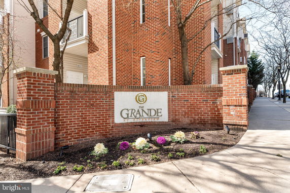Front view of a brick apartment building with a sign reading 'The Grande.'
