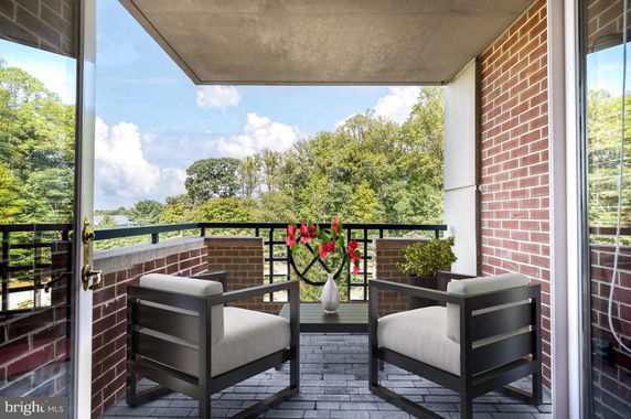 Balcony with chairs overlooking a scenic view of trees.