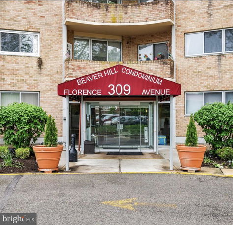 Front view of a condominium entrance with a red canopy above glass doors.
