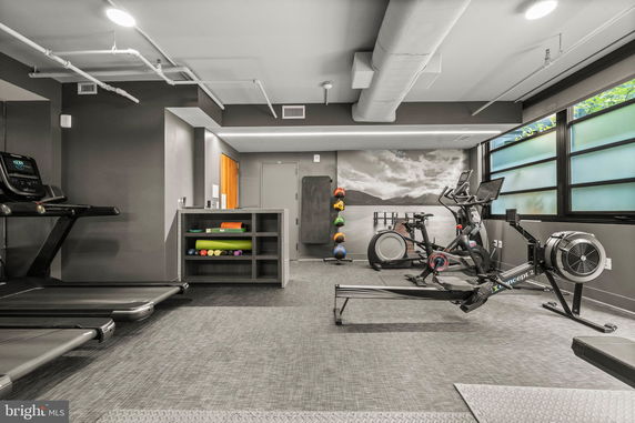 Modern indoor gym with exercise equipment and large windows.