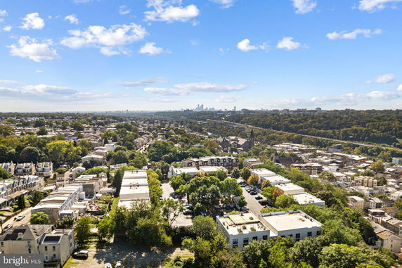 Panoramic view of a cityscape with buildings and greenery, seen from above.