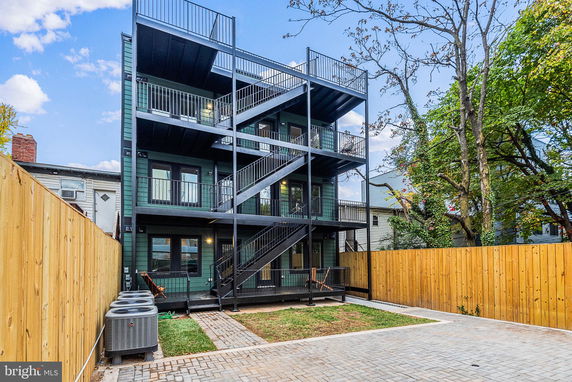 Rear view of a multi-level building with balconies and an exterior staircase.