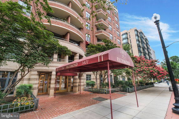 Front view of a multi-story residential building with a red awning entrance.