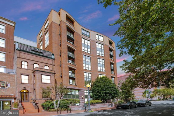 Front view of a multi-story brick building with balcony windows.