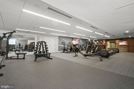 Interior view of a gym with exercise equipment including treadmills and weights.