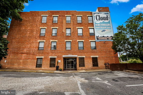 Front view of a multi-story brick building with large windows and an entrance at the ground level.