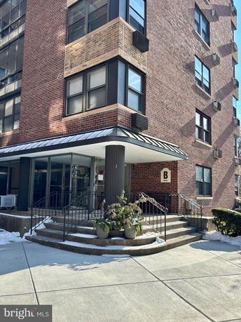 Front view of a multi-story brick building with a main entrance and stairs.