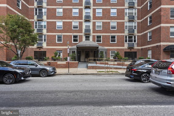 Front view of a multi-story brick apartment building with a central entrance.