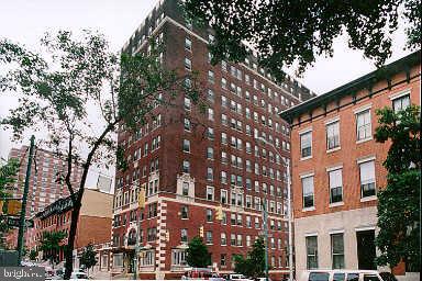Front view of a multi-story brick building with surrounding trees.