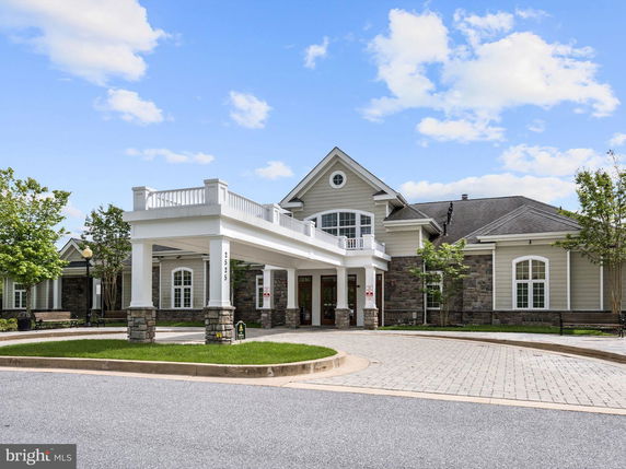 Front view of a large building with a covered entrance and stone accents.