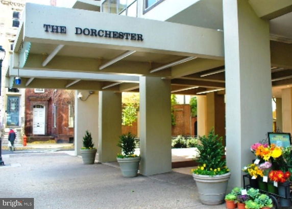 Entrance view of a building with a covered walkway and potted plants.