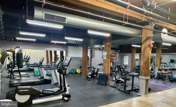 Interior view of a gym with exercise equipment including treadmills and weights.