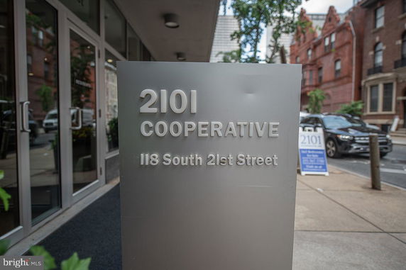 Front entrance of a cooperative building with a sign displaying the address.