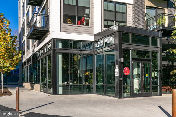 Front view of a modern multi-story building with glass storefronts.