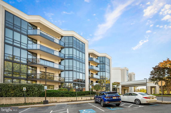 Front view of a modern multi-story building with large glass windows and balconies.