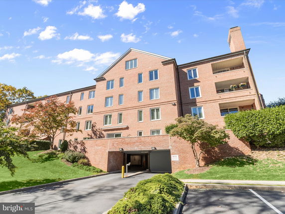 Front view of a multi-story brick building with an entrance to a covered parking area.