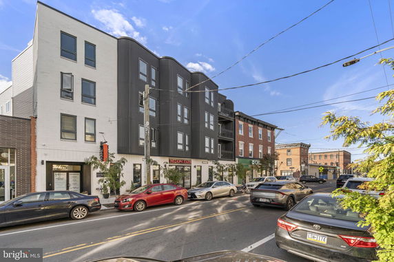 Front view of a modern multi-story building with commercial spaces on the ground floor.