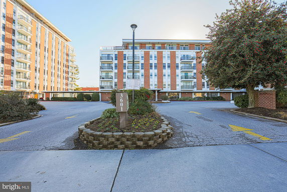 Front view of a multi-story apartment building with a parking area in front.