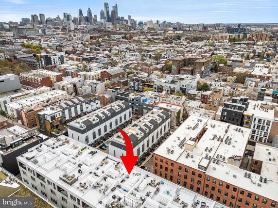Aerial view of a dense urban area with various buildings and a city skyline in the background.